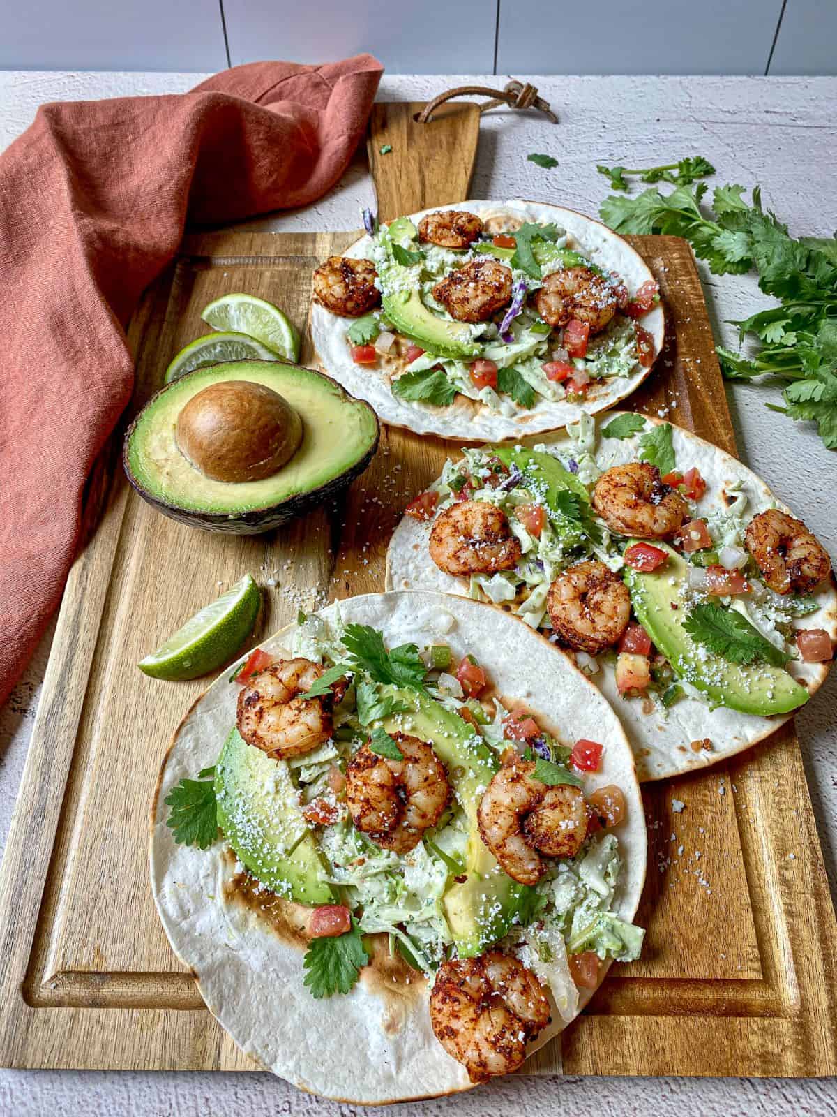 Shrimp tacos with many toppings on flour tortillas.