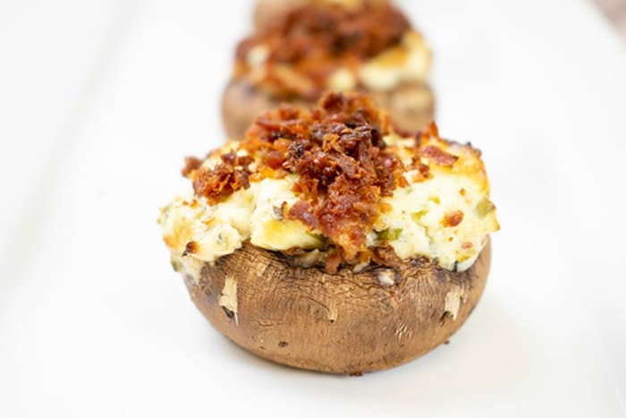 Blue cheese and bacon stuffed mushrooms on a white plate.