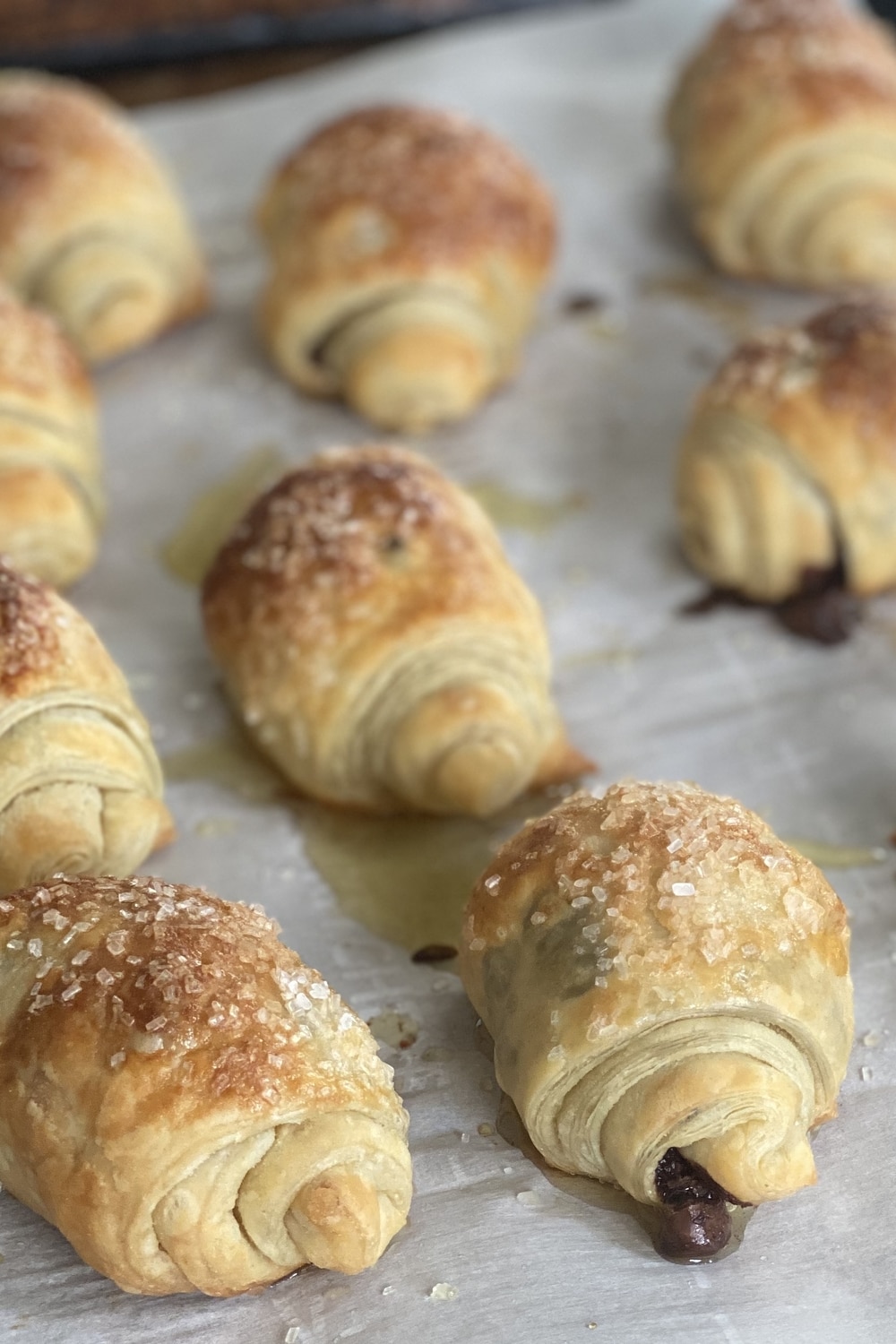 Mini chocolate chip pastry rolls on a parchment lined baking sheet.