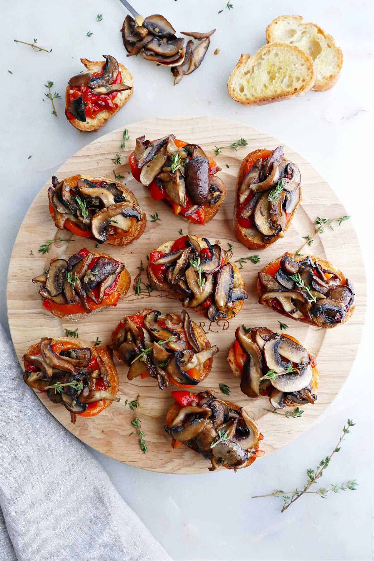 Bruschetta with mushrooms and roasted peppers on a wooden platter.