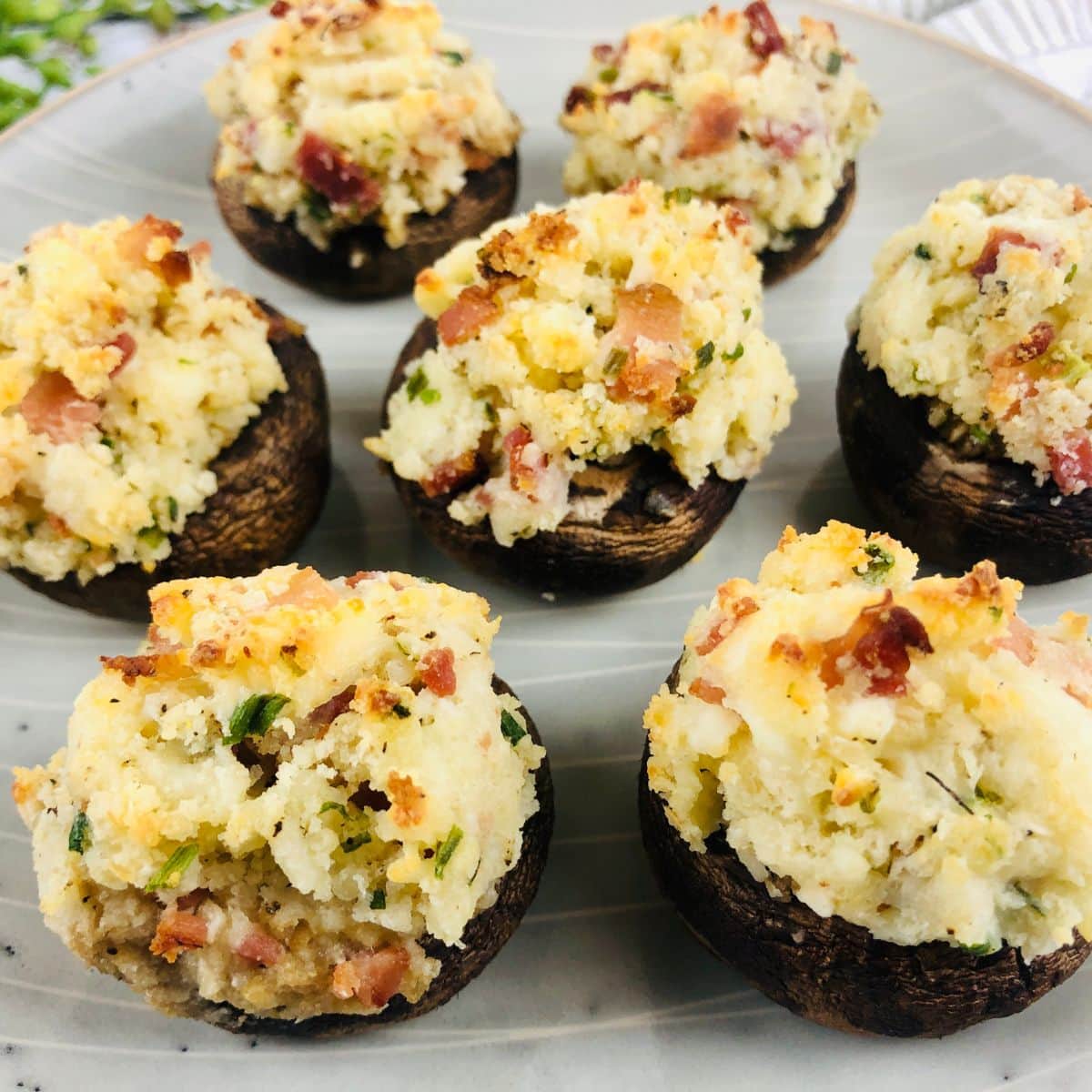 Cheese and bacon stuffed mushrooms on gray plate.