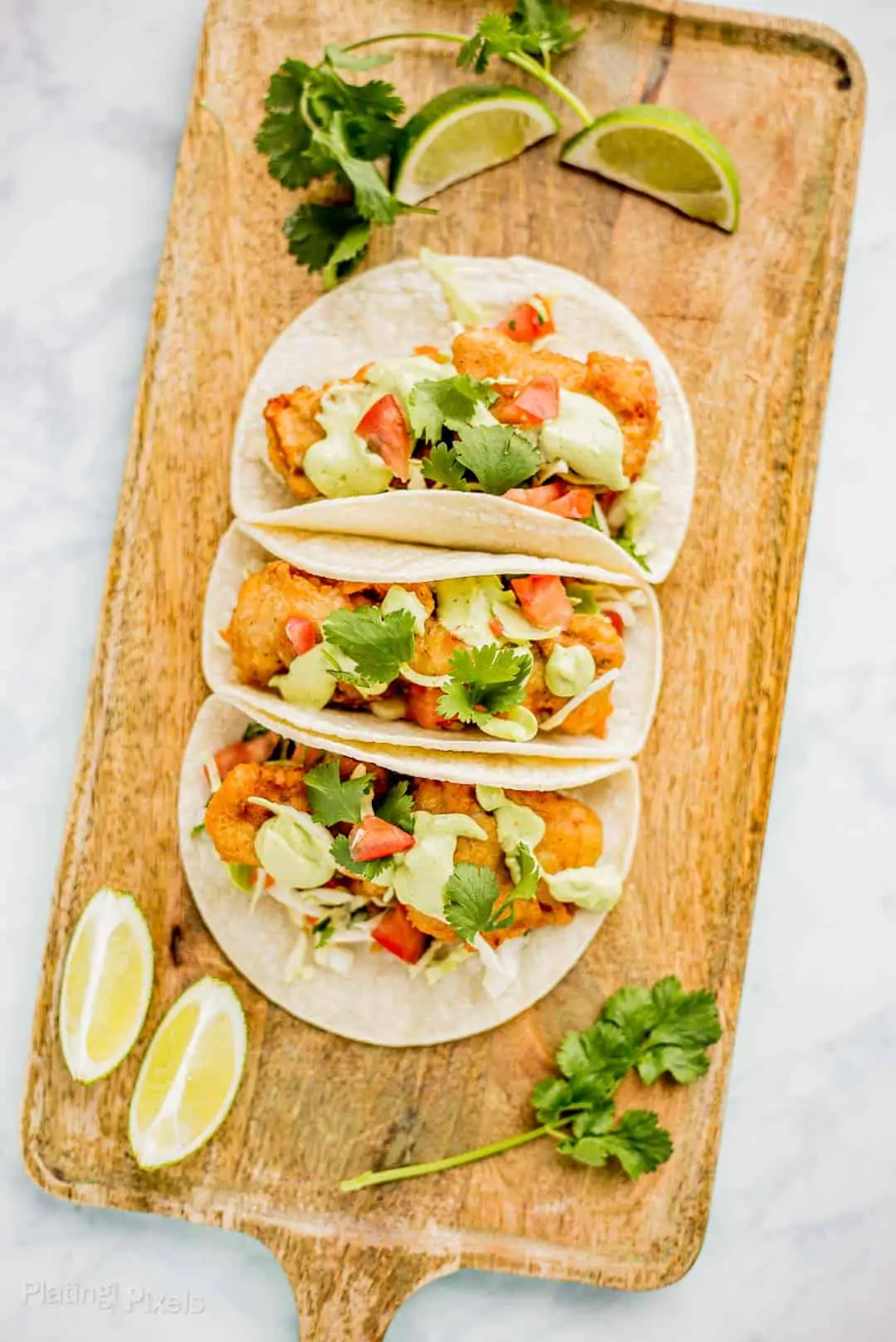 Battered fish tacos on a wooden serving platter.