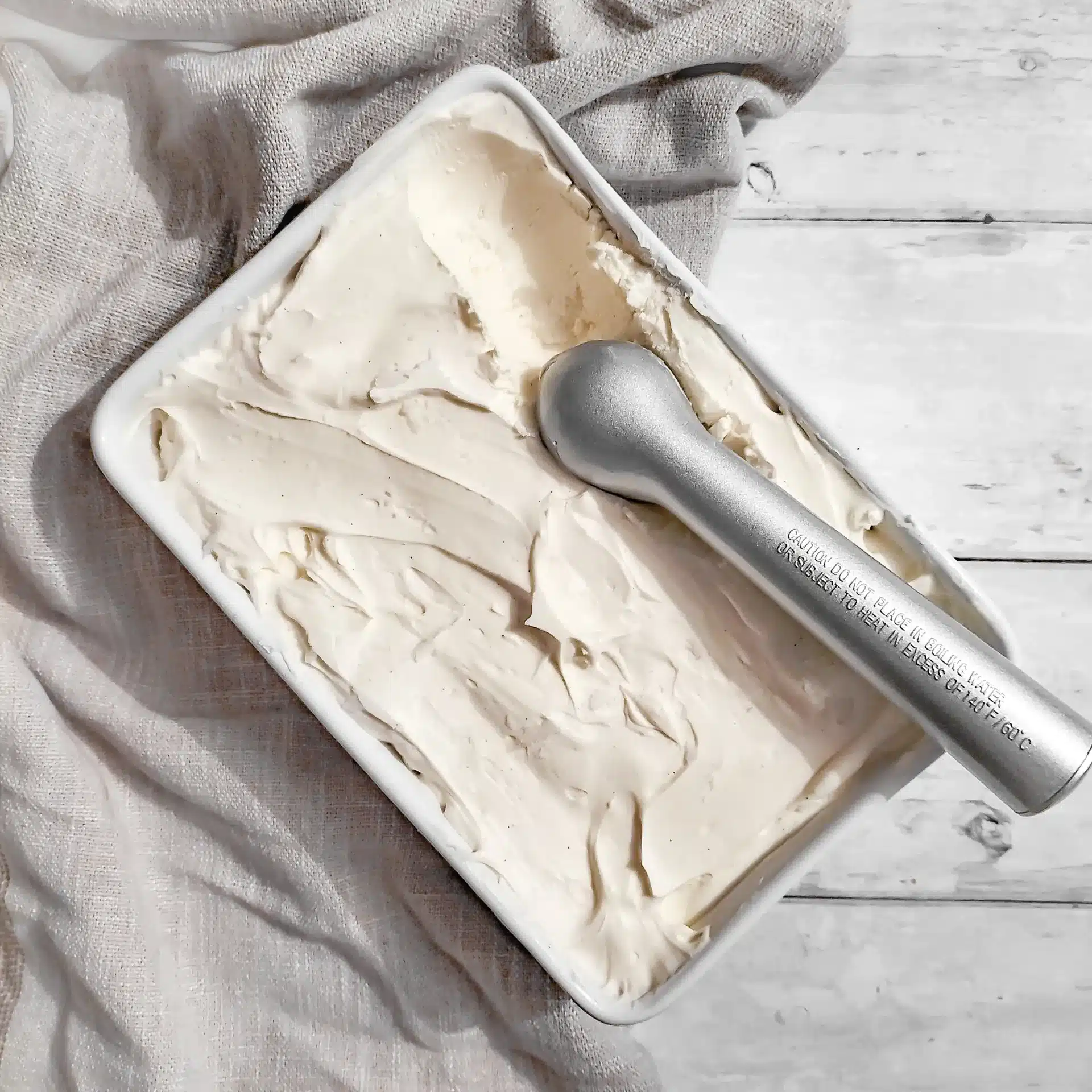 Vanilla ice cream in a square container and a scoop.