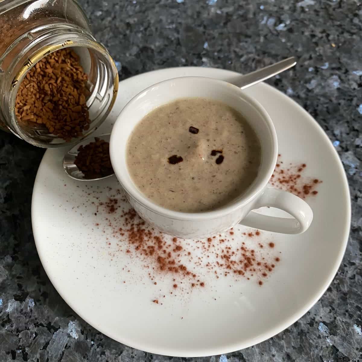 Creamy mushroom soup served in a cappuccino cup dusted with cocoa powder.