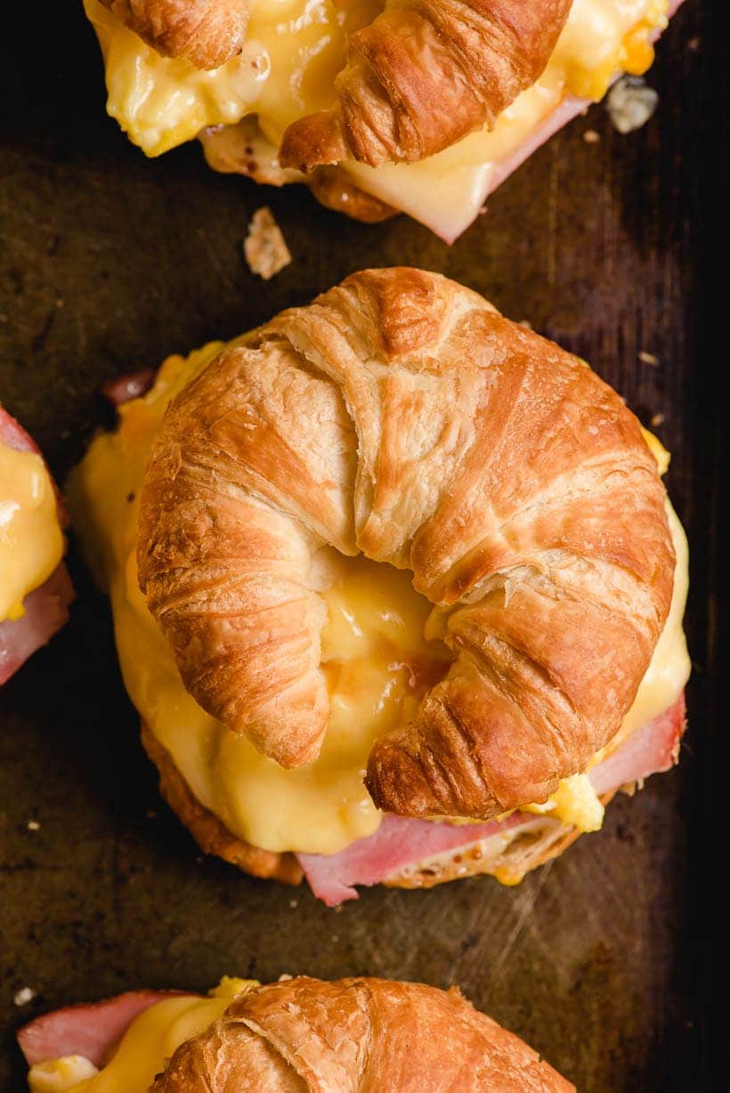 Breakfast croissant sandwiches on a pan.