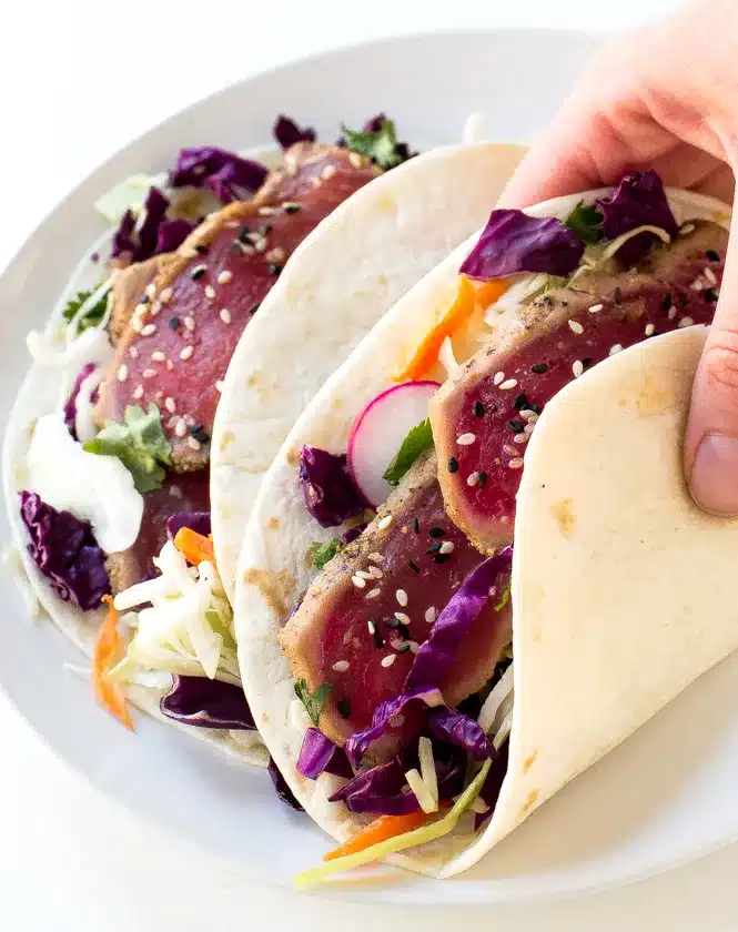 Ahi tuna tacos with radish and cabbage on flour tortillas.