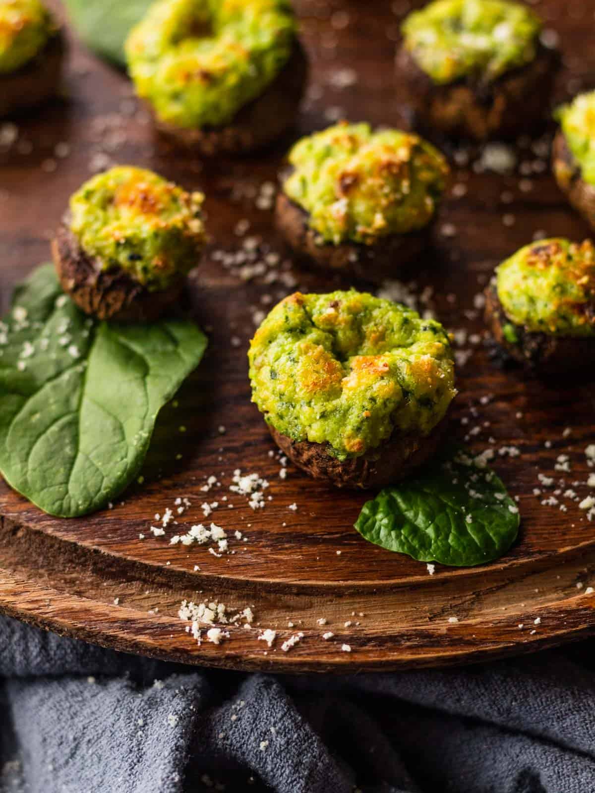 Spinach and ricotta stuffed mushrooms on a round wooden serving tray.