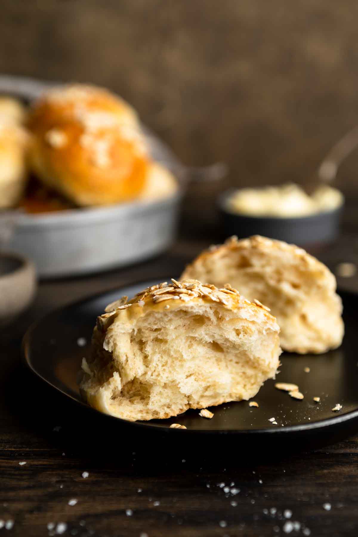 Old fashioned oatmeal dinner rolls on a black plate.