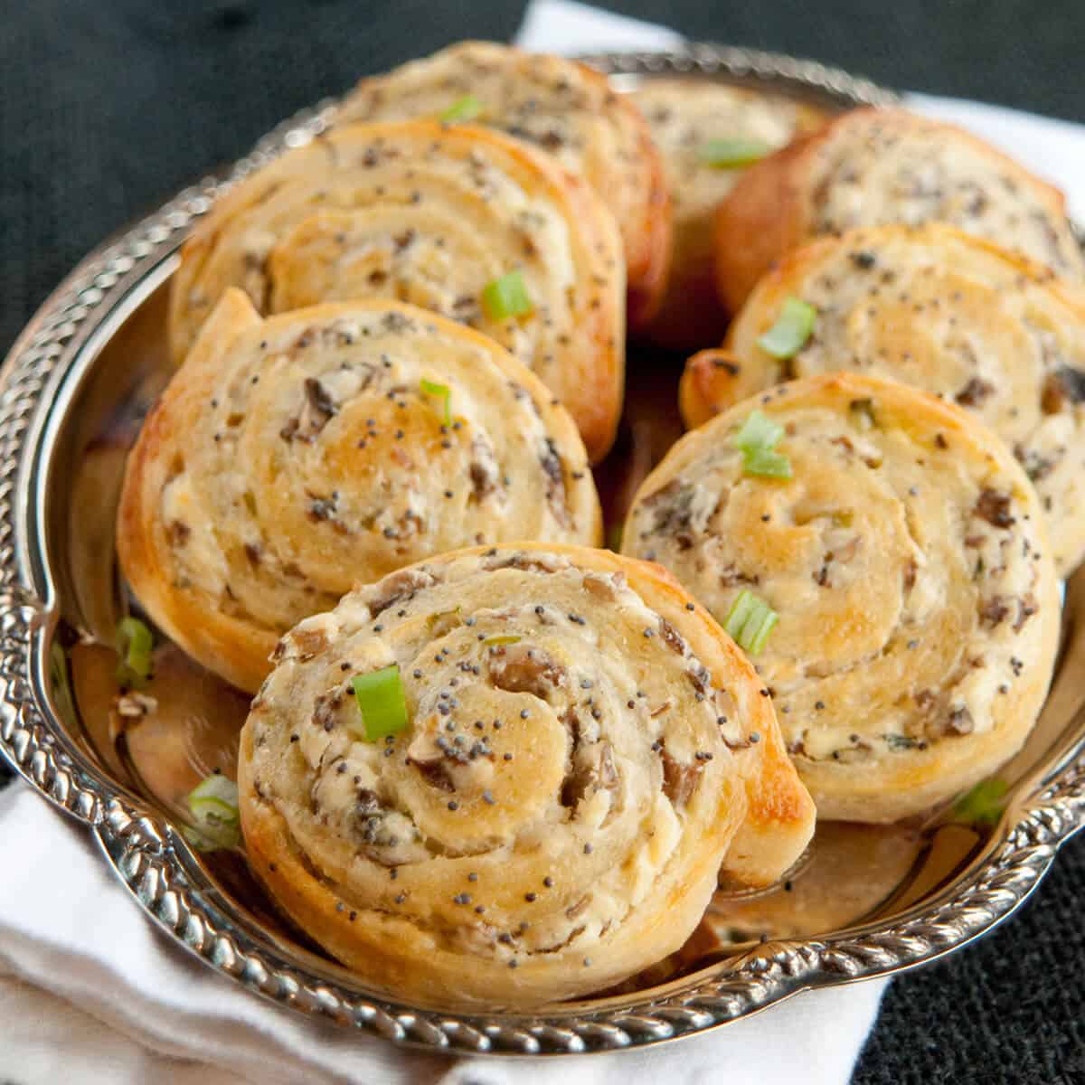 Cheesy mushroom pinwheels on a silver platter.