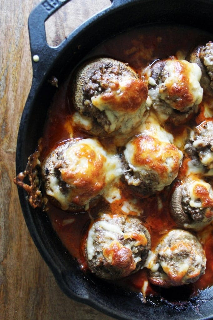 Sausage stuffed mushrooms with sweet and spicy marinara in a cast iron pan.