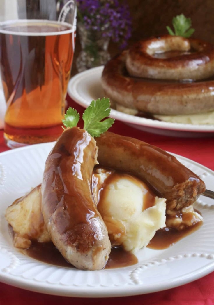 Cumberland sausage with mashed potatoes and gravy  with a glass of beer.
