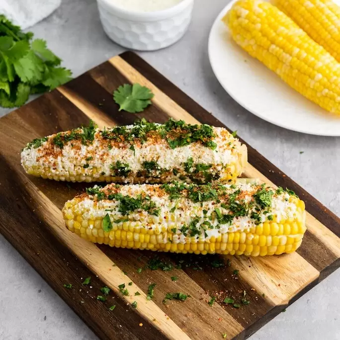 Mexican street corn on a cutting board.