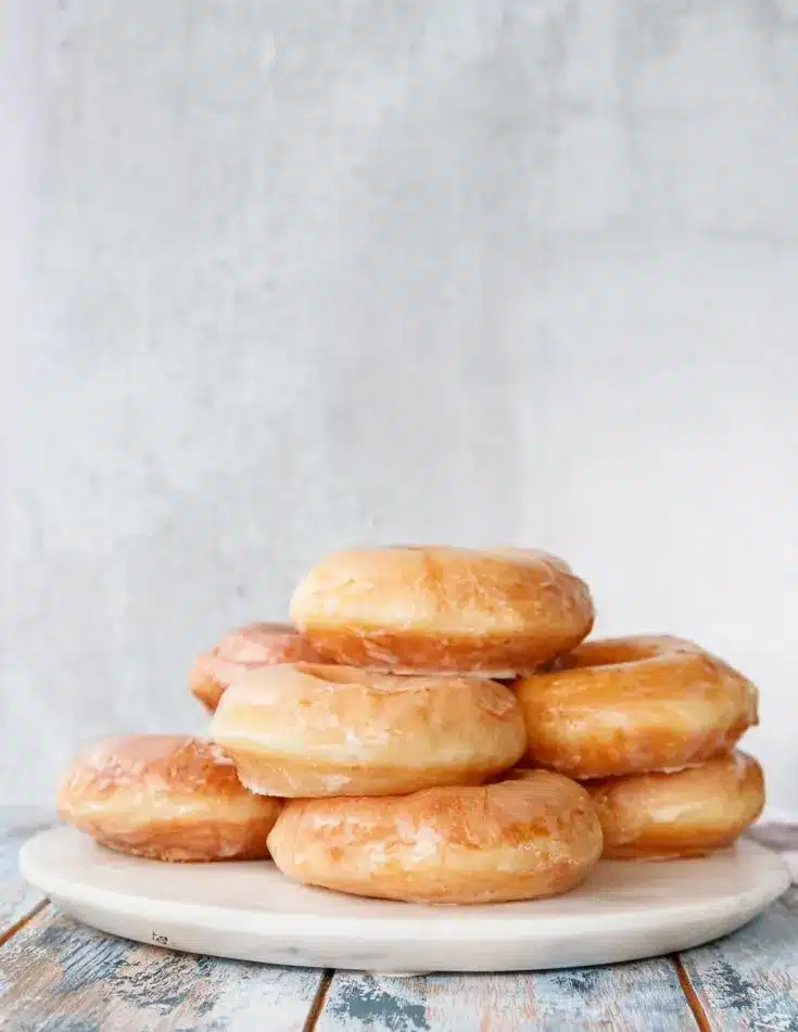 Stack of sourdough discard glazed donuts on a marble serving tray.