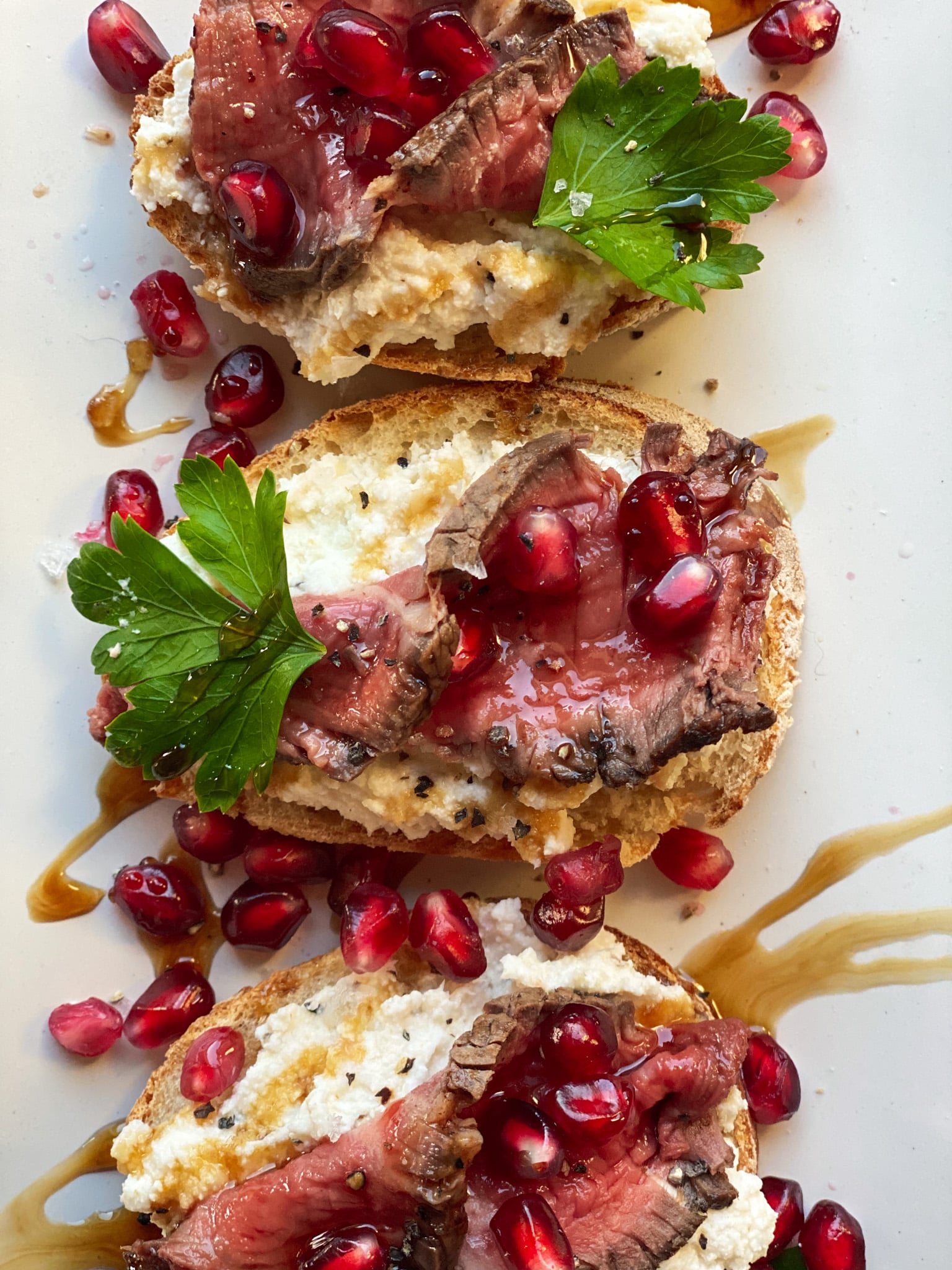 Steak crostinis with horseradish ricotta on a white background.