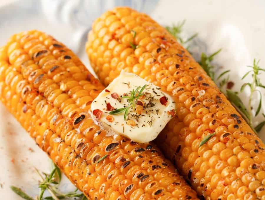 Air fryer corn on the cob with a pat of butter and herbs.
