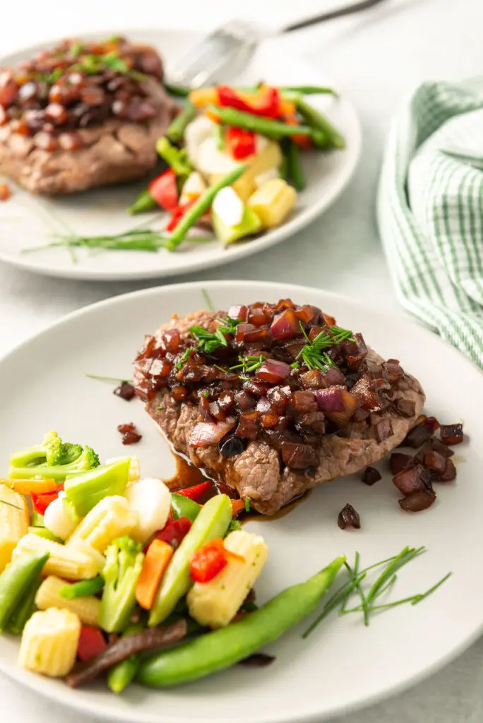 Chaliapin steak on a white plate with mixed vegetables.