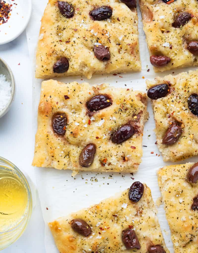 Sliced focaccia with olives on parchment paper.