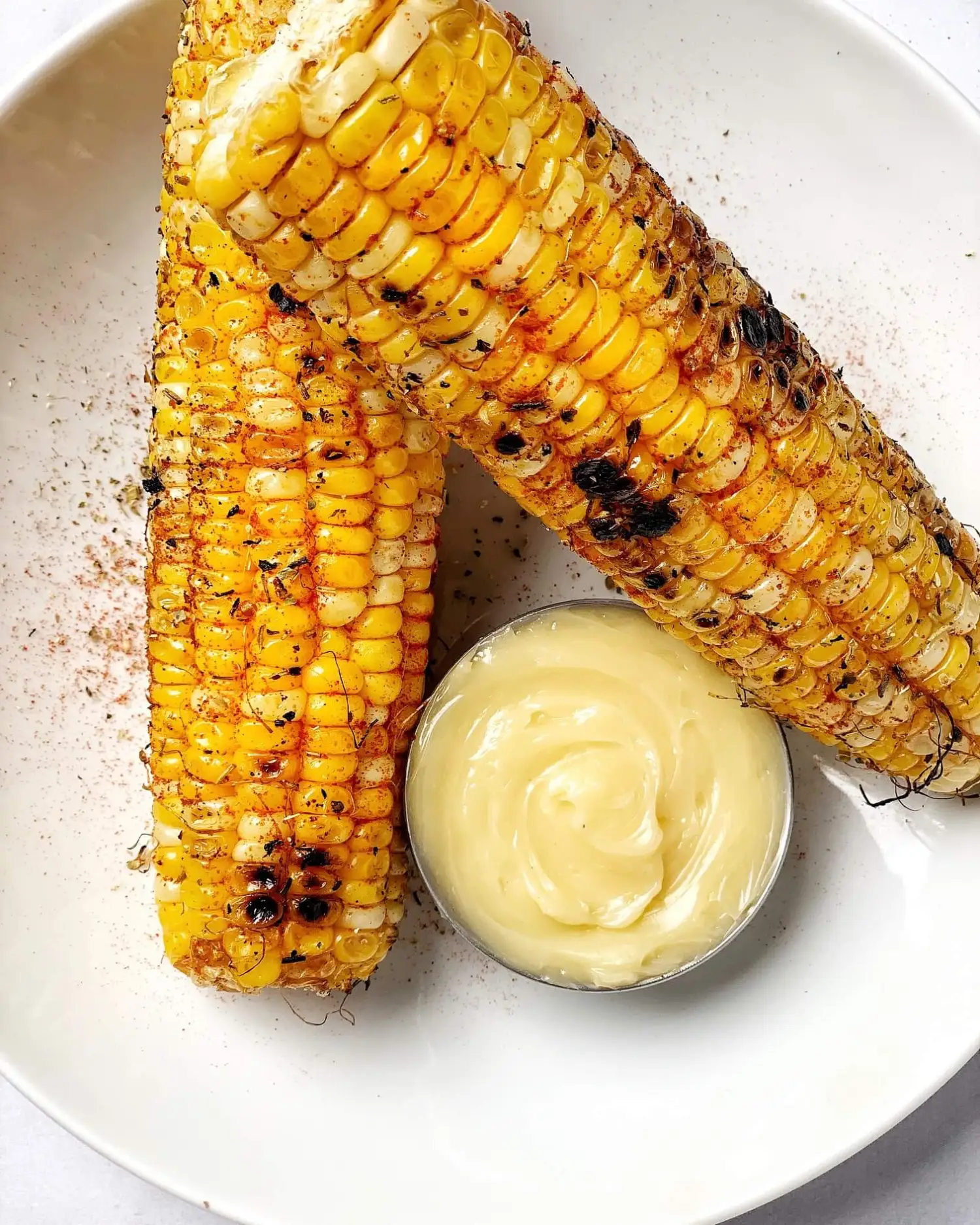 Herb roasted corn with hot honey butter on a white plate.