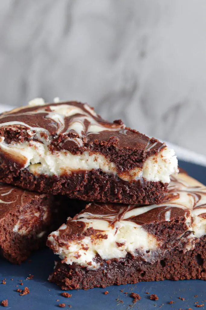 Stack of cheesecake brownie slices on a blue plate.