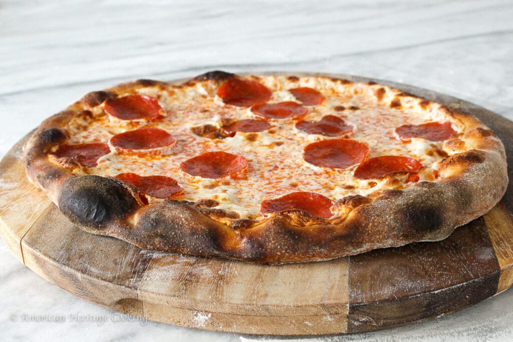 Sourdough pizza on a wooden cutting board.