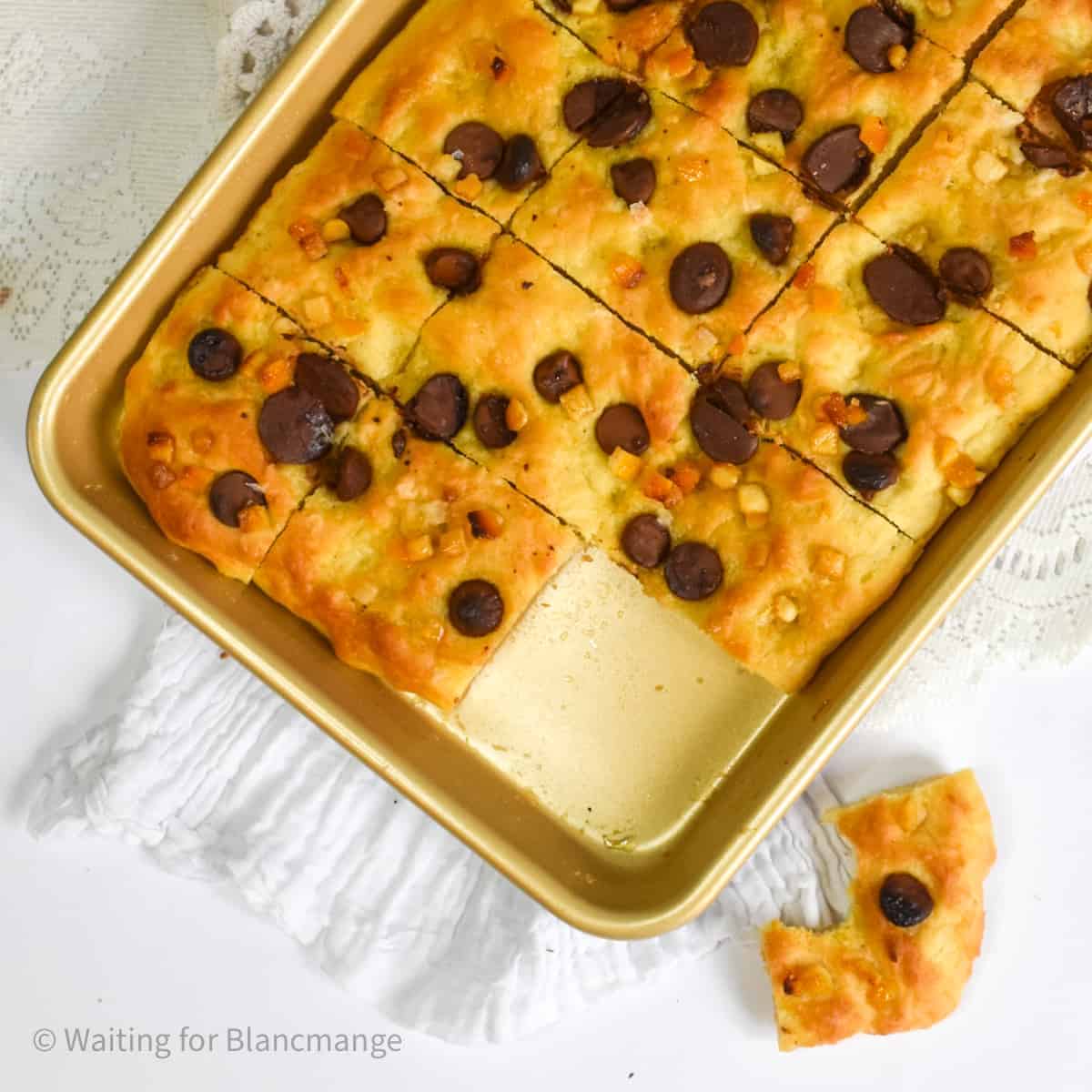 Sliced sweet chocolate and orange focaccia in a baking pan.