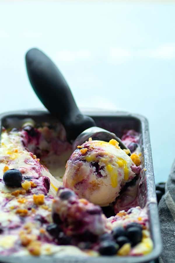 Lemon curd shortbread blueberry frozen yogurt in a container with scoop.