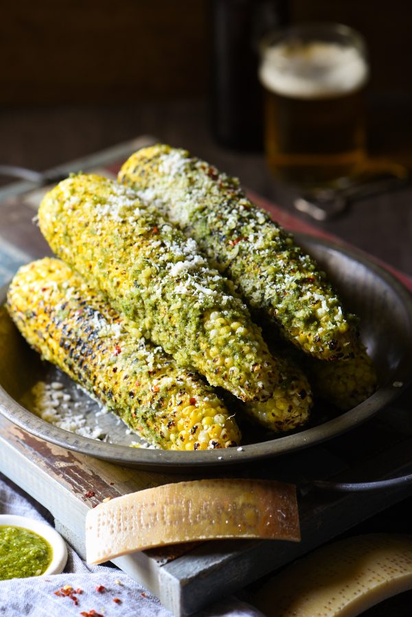 Stack of grilled parmesan-pesto sweet corn on a pan.