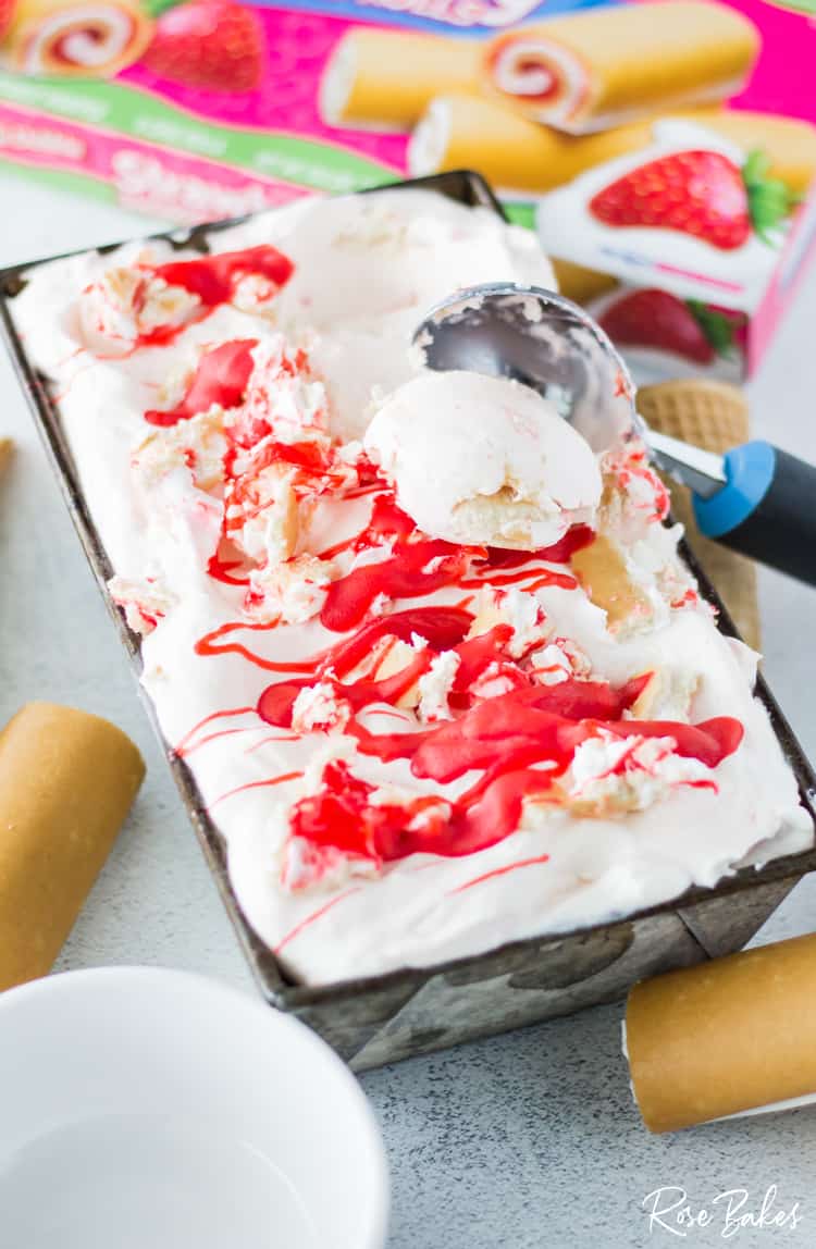 Scooped out shortcake rolls ice cream from container with box of strawberry rolls in the background.