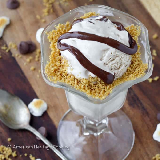 Marshmallow ice cream with graham cracker sand and chocolate sauce in a glass serving bowl.