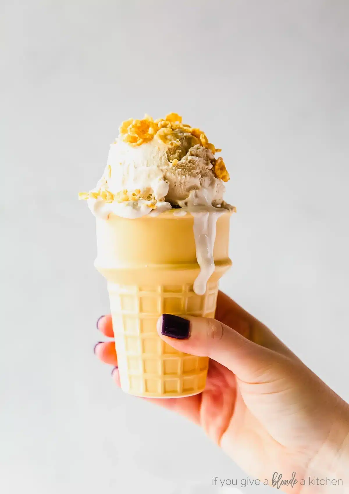 Hand holding cake cone with cereal milk ice cream.