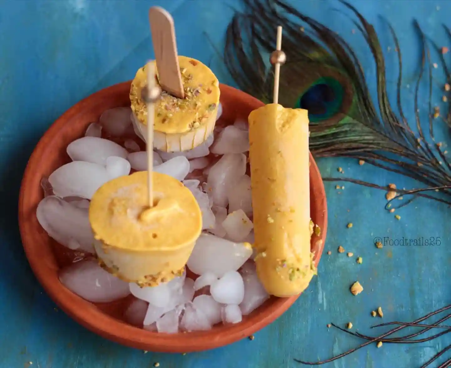 Mango kulfi ice cream pops on ice in a bowl.
