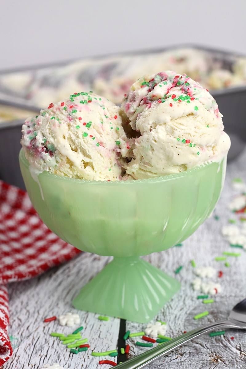 Christmas cookie ice cream with festive red and green sprinkles in a green bowl.