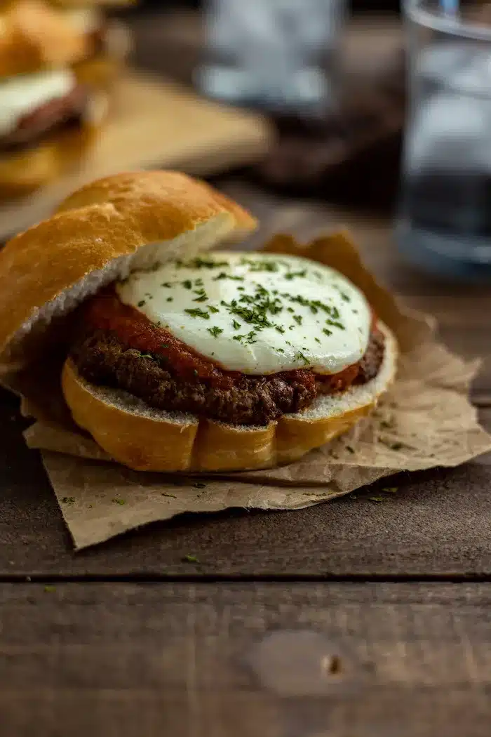 Burger with pizza sauce and mozzarella cheese on a bun.