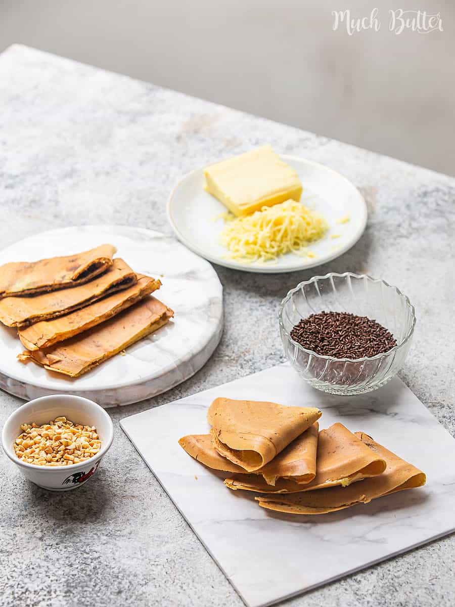 Crispy thin pancakes with chocolate sprinkles and peanuts in bowls on the side.