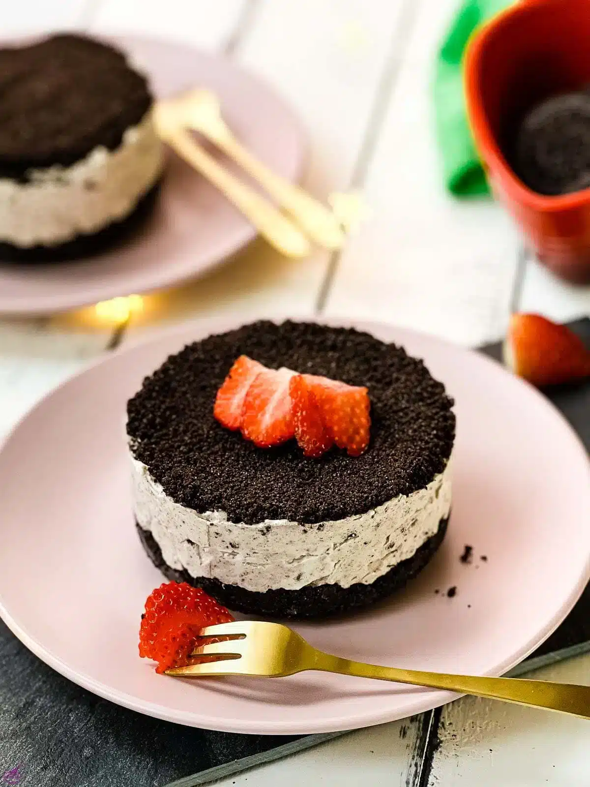 No bake Oreo cheesecake with strawberry slices on a pink plate.