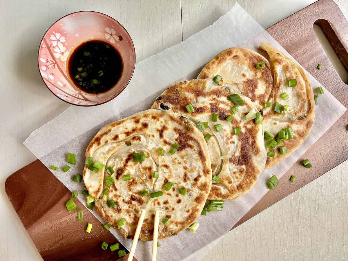 Taiwanese green onion pancakes on a parchment paper with dipping sauce.