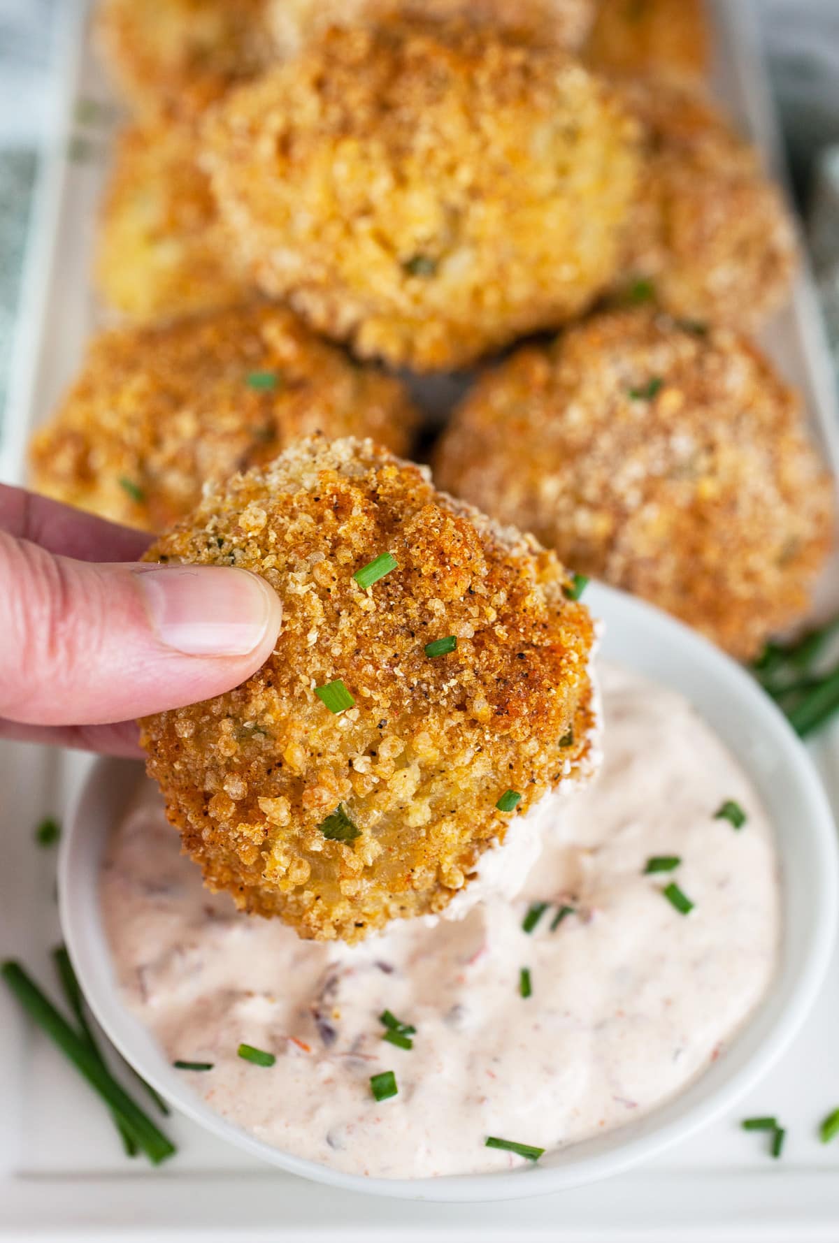 Hand dipping rice ball in chipotle mayo.