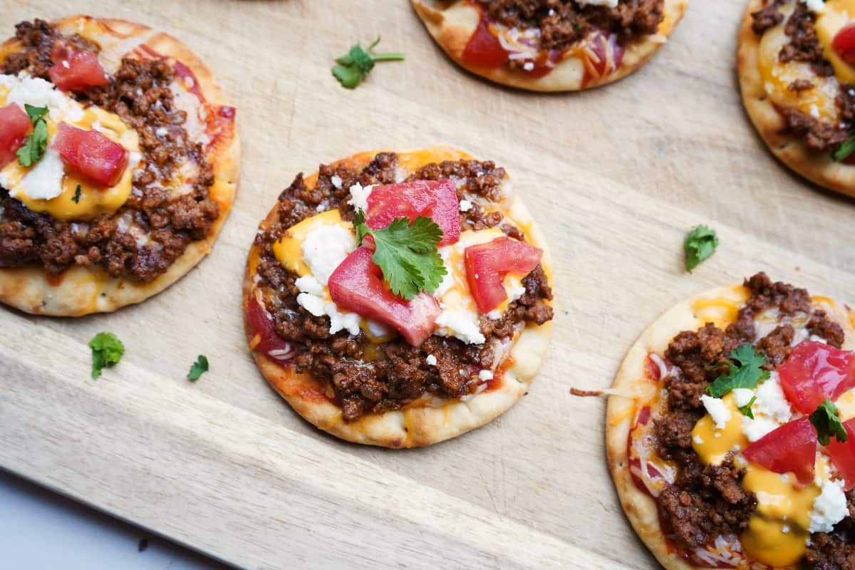 Tiny Mexican pizzas on a cutting board.