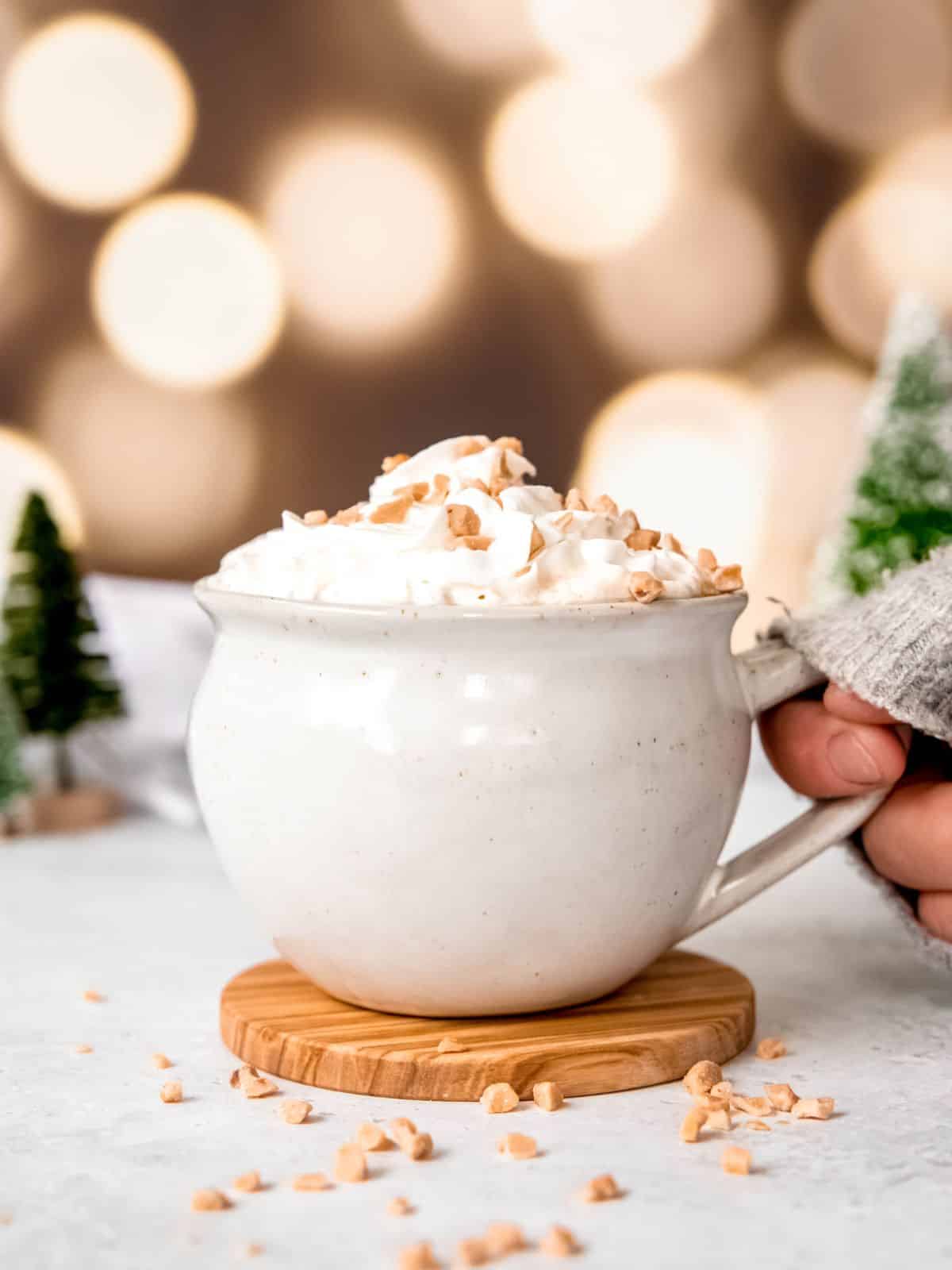 Hand holding a mug filled with caramel brulee latte.