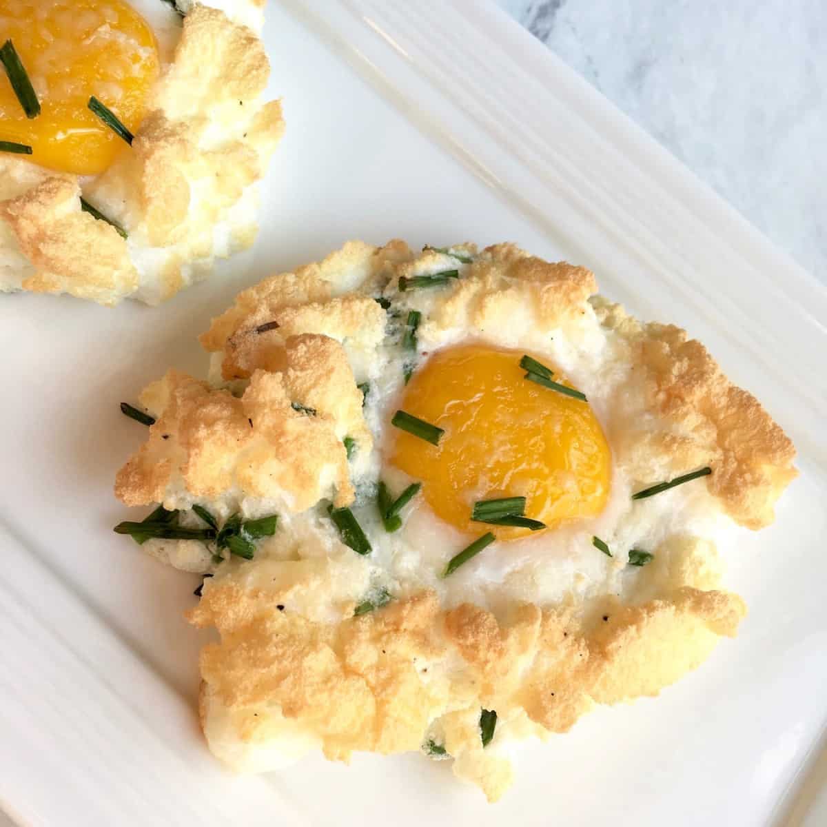 Square plates with cloud eggs sprinkled with herbs.