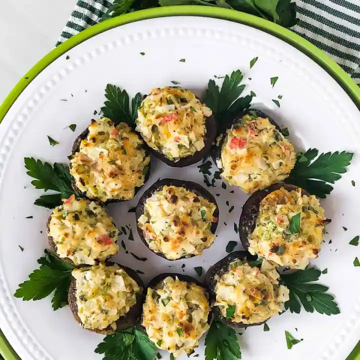 Crab stuffed mushrooms with cream cheese on a white plate.