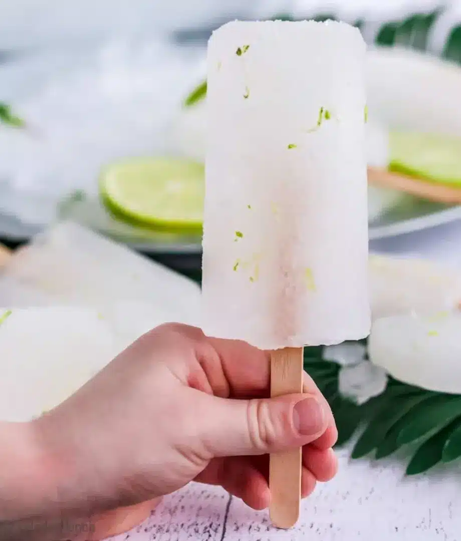 Hand holding limeade popsicles.