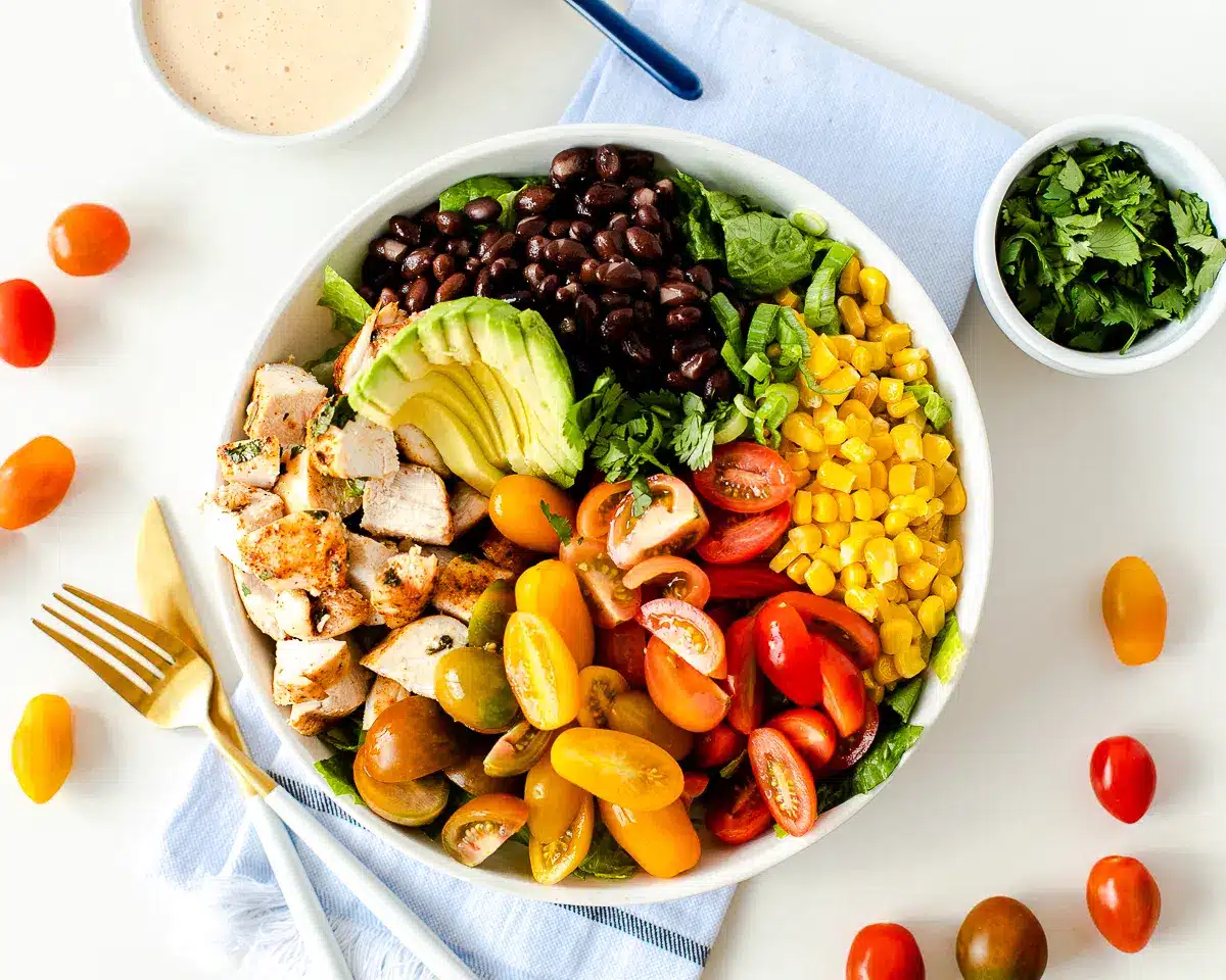 Southwest chicken salad with beans, corn, avocado, sliced cherry tomatoes, and chicken.