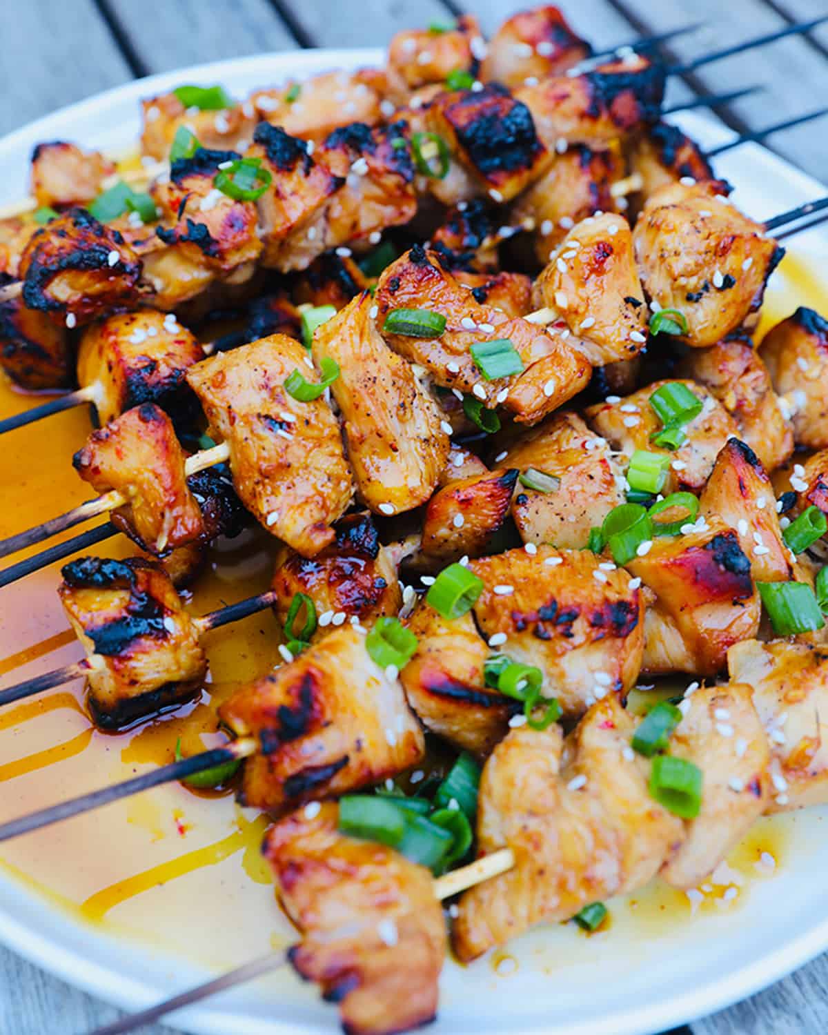 Grilled honey garlic chicken skewers on a white plate.