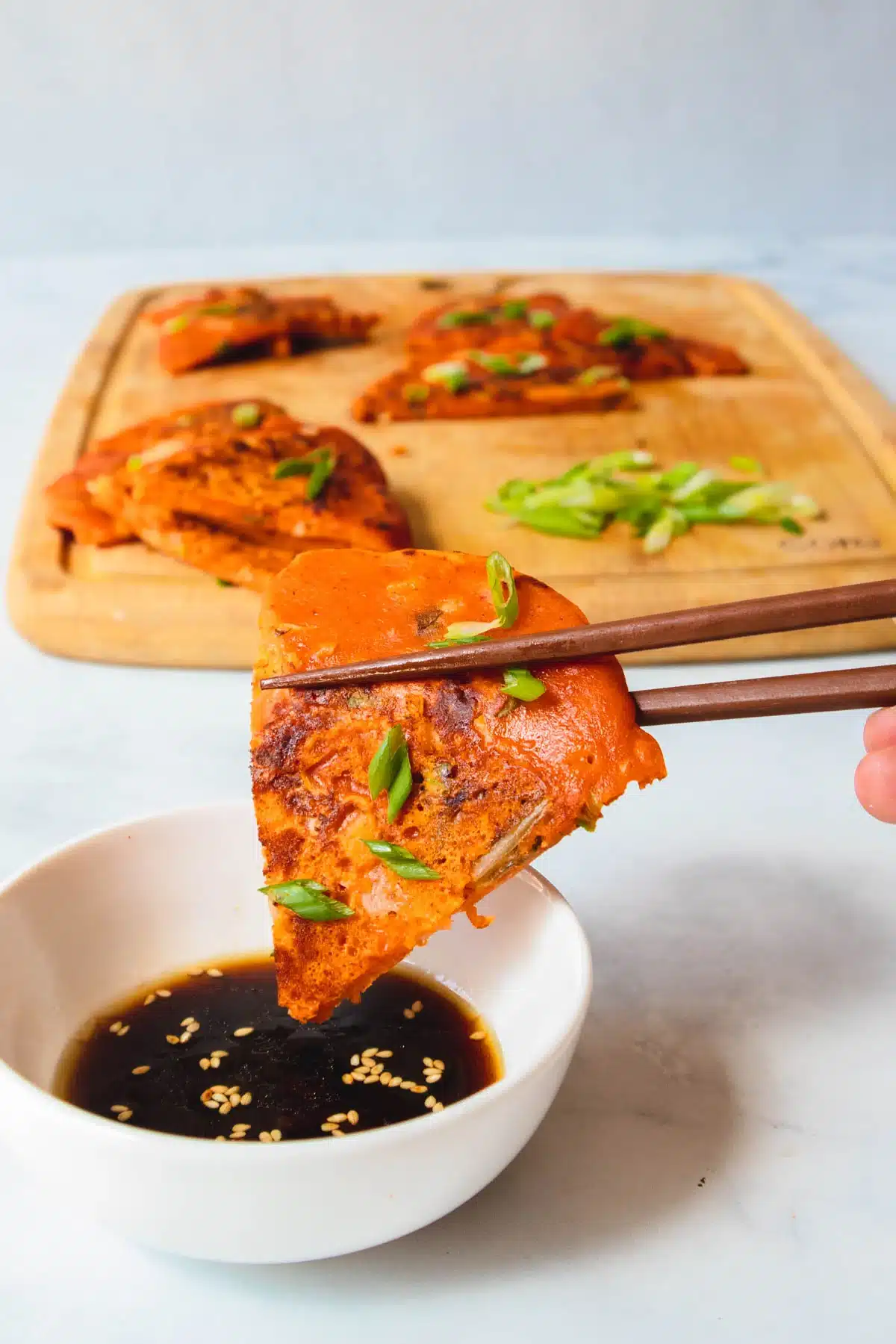 Chopsticks holding a piece of kimchi pancake.