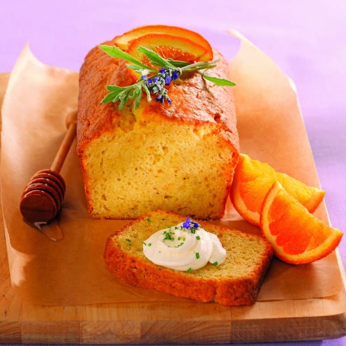 Lavender cake on parchment with honey comb and orange slices.