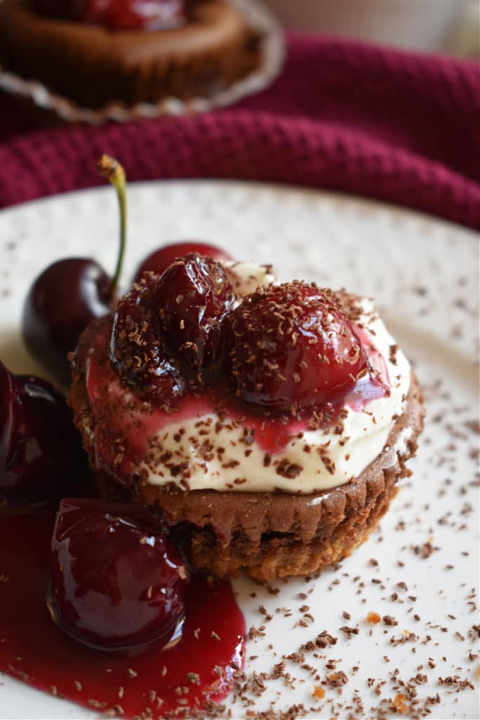 Chocolate mini cheesecake with cherry pie filling and chocolate shavings.