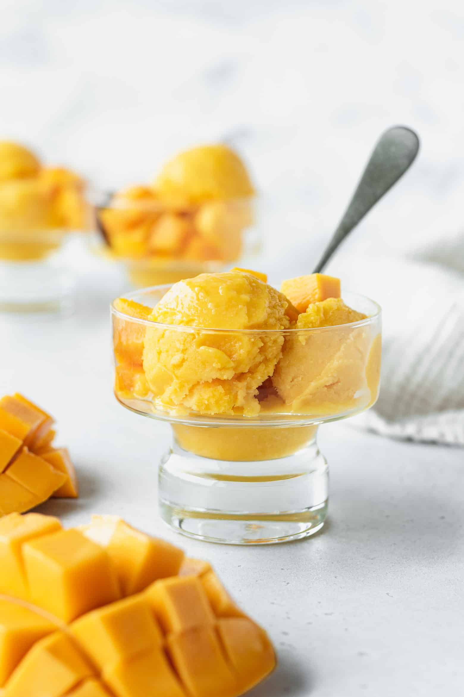 Glass full of mango lime sorbet with a spoon.