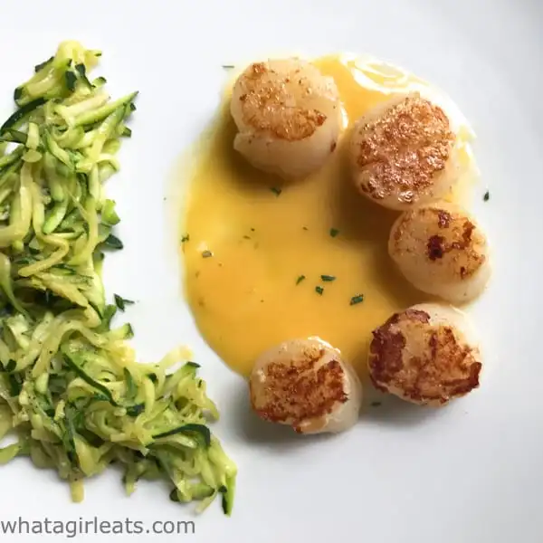 Scallops with sauce on a plate.