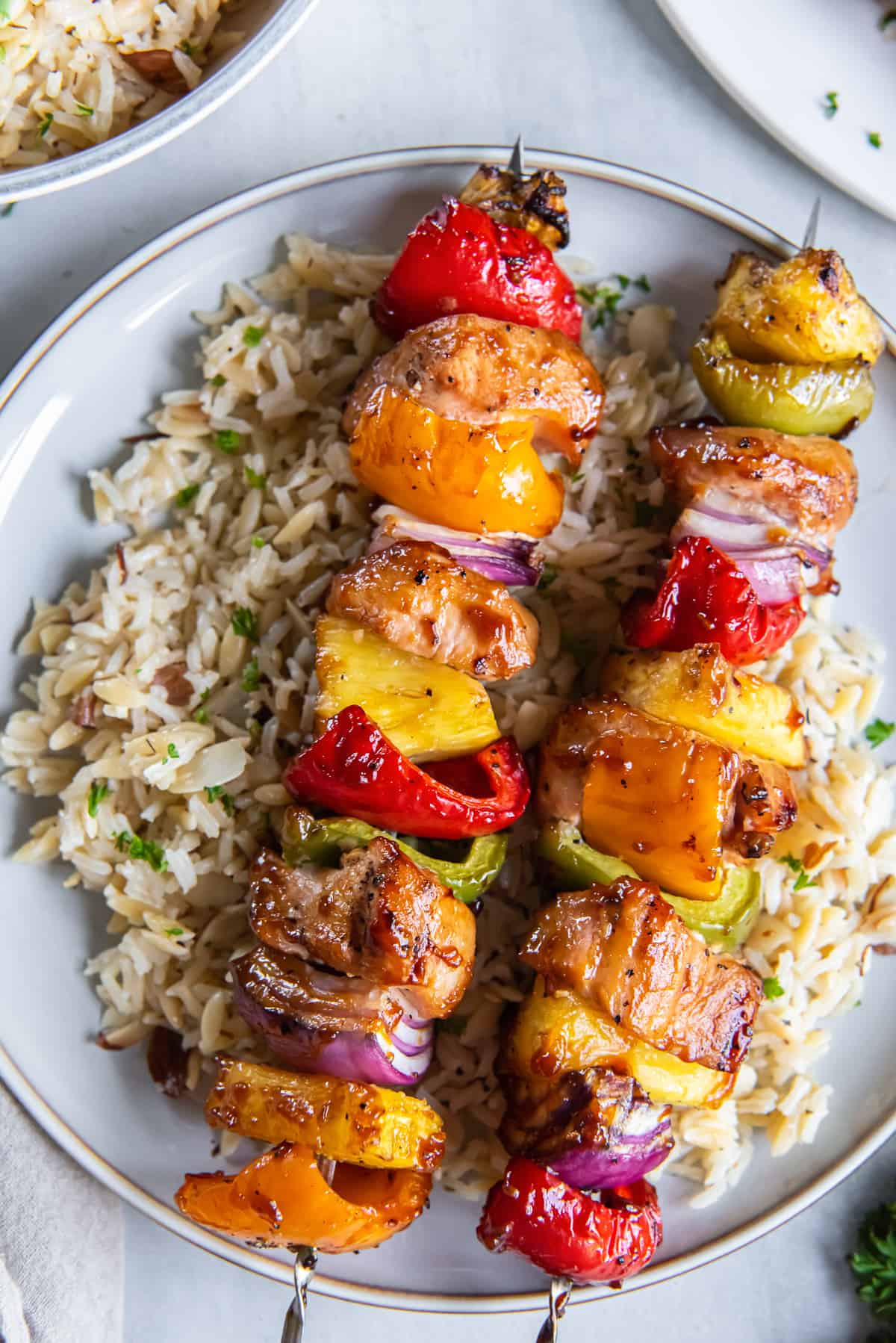 Pineapple chicken kabobs with peppers, pineapple atop of rice.